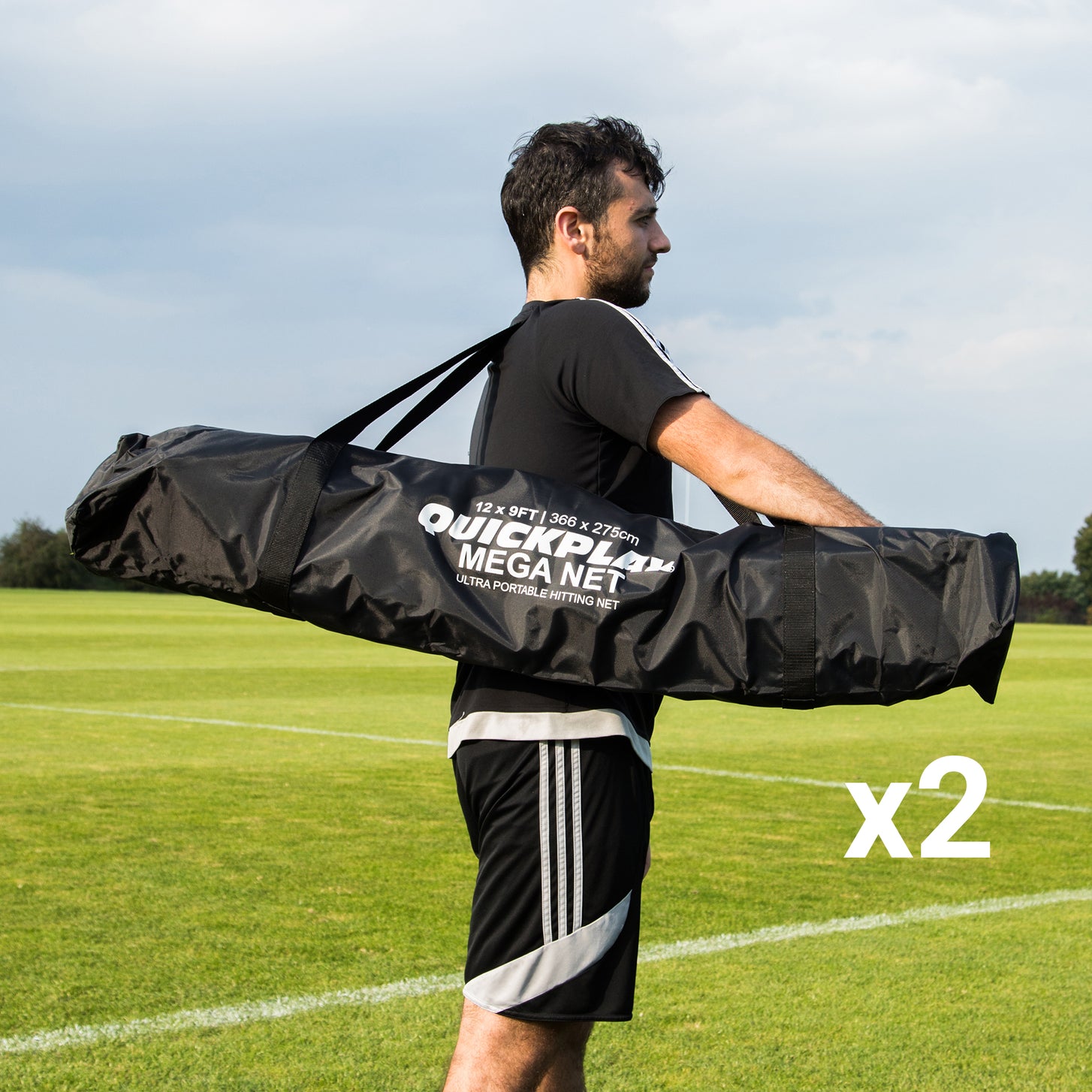 Man carrying a black QUICKPLAY MEGA NET bag on his shoulder across a grass field, with the text "x2".